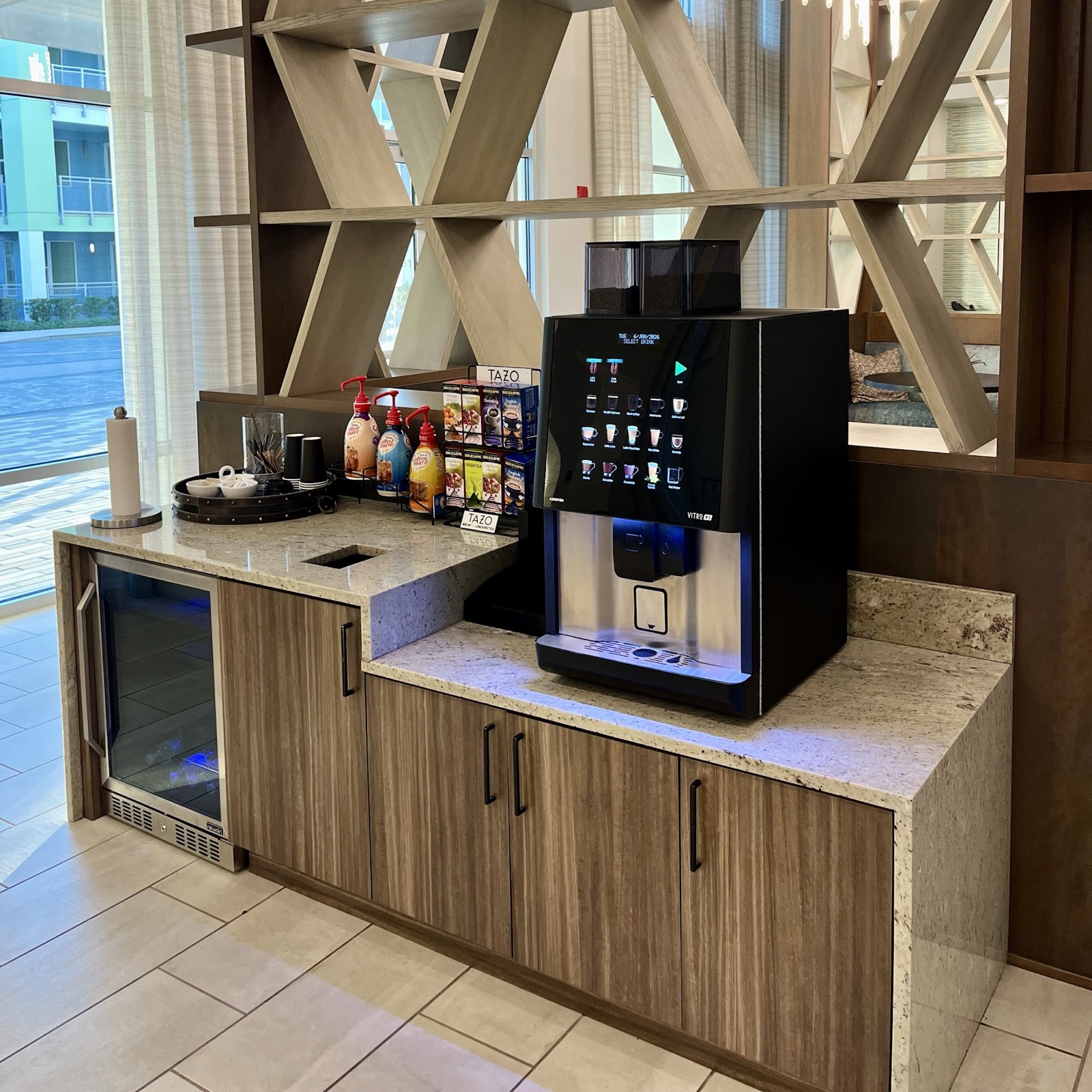 Apartment clubhouse coffee bar with a bean-to-cup machine, creamers and a drinks fridge