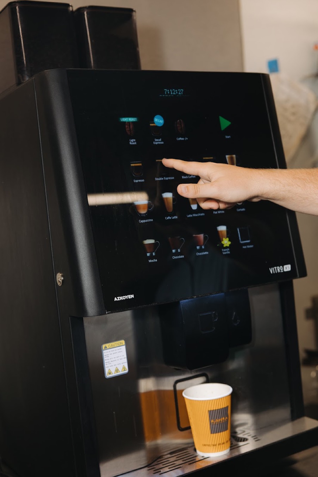 Finger choosing a drink on a bean-to-cup machine touchscreen